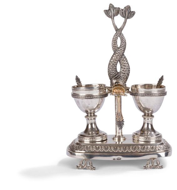 ITALIE XIXe SIÈCLE

Paire de salières en argent et six pelles à sel en vermeil et leur support reposant sur une base quadripode de dauphins en rappel sur la prise centrale. Porte-cuiller et salière en vermeil de part et d'autre de la tige centrale.

FLORENCE, XIXe SIÈCLE

Pas d'orfèvre apparent

Poids : 381,80 g - hauteur : 18,7 cm