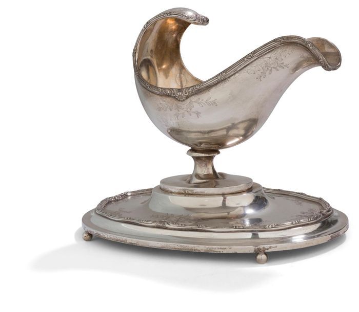 PORTUGAL XXe SIÈCLE

Saucière en argent (916‰) sur sa terrasse reposant sur quatre pieds boule. De forme ovale, le plateau à doucine rehaussé de rangs de filets feuillagés en rappel sur la bordure de la saucière ciselés de feuillages.

Poids : 1282,50 g - longueur : 28,5 cm - largeur : 19,7 cm - hauteur : 22,8 cm