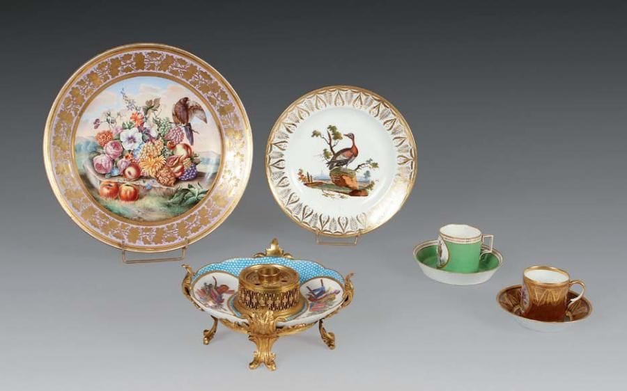 Europe
Sèvres. Encrier en porcelaine et bronze doré formé d'un plateau circulaire en porcelaine tendre de Sèvres à décor polychrome de trophées dans deux réserves ovales sur fond Taillandier bleu, il repose sur quatre pieds rocailles en bronze doré et au centre un encrier en bronze doré. La porcelaine du XVIIIe siècle, vers 1770, la monture en bronze doré du milieu du XIXe siècle. L: 20 cm.