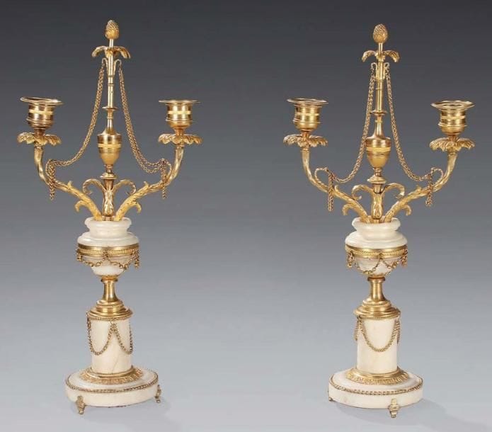 Paire de flambeaux en marbre blanc et bronze très finement ciselé à l'or mat et l'or brillant. Ils sont à deux bras de lumière, à décor de palmettes. Au centre un thyrse stylisé à vase à l'Antique, graine et chaîne, émerge d'un vase reposant sur une colonne cylindrique à petits pieds. Époque Louis XVI H: 42 cm - L: 21 cm