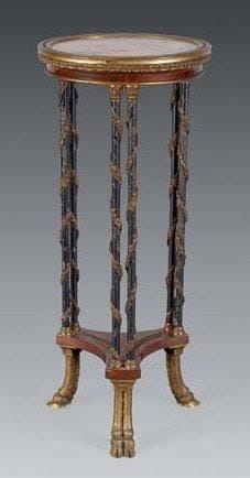 Guéridon En bois de placage marqueté en feuilles. La ceinture à doucine. Riche ornementation de bronzes ciselés et dorés à décor d'encadrement à feuilles d'acanthe. Le piétement à double colonne en métal bleui, rehaussé de guirlandes fleuries et feuillagées. Piétement tripode à tablette, reposant sur des doubles pieds à sabot. Plateau probablement en onyx, encastré. Modèle de WEISWEILLER Style Louis XVI, fin du XIXe siècle H: 76 cm - D: 32,5 cm