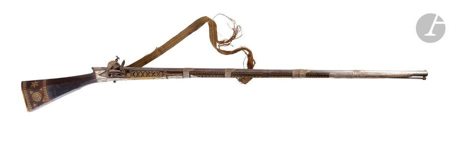 Fusil à silex ottoman « Tufek ».
Canon maintenu par des bagues de métal argenté, poinçonné et ciselé au tonnerre. 
Platine à la Morlaque doublée de métal argenté. Fût garni à l’extrémité d’une longue bague en métal argenté ciselé, richement incrusté de plaquettes de nacre à décor losangique et de motifs en laiton. Crosse en noyer, à pans, décorée en suite. A plaque de couche en os. 
Avec reste de bretelle en passementerie. 
B.E. Première partie du XIXe siècle. 