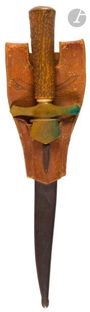 Couteau de vènerie.
Poignée en bois de cerf. Monture en laiton, garde à clavier découpé gravé « JA ». Lame à dos. Fourreau en tôle de fer bronzée. 
Gousset en cuir brun. 
B.E. Vers 1900. 