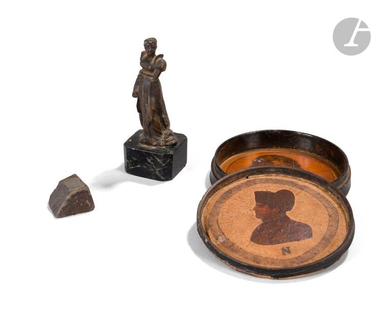 Boite ronde en carton garnie à l’intérieur de deux gravures de l’Empereur Napoléon Ier et du Roi de Rome.
On y joint une statuette de Joséphine en bronze, sur socle en marbre (9 cm) et un morceau de pierre noire provenant de Sainte-Hélène.