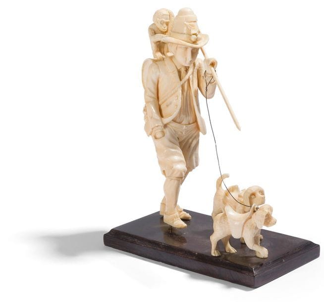 Le montreur d’animaux en ivoire sculpté en ronde-bosse. L’homme est représenté marchant, la main droite dans la poche de son pantalon ; il porte un bâton sur une épaule auquel est suspendu un tambour sur lequel se tient assis un singe ; il a un baluchon dans le dos et tient en laisse deux petits chiens ; sur un socle en bois noirci.
Dieppe, XIXe siècle
H : 16 cm