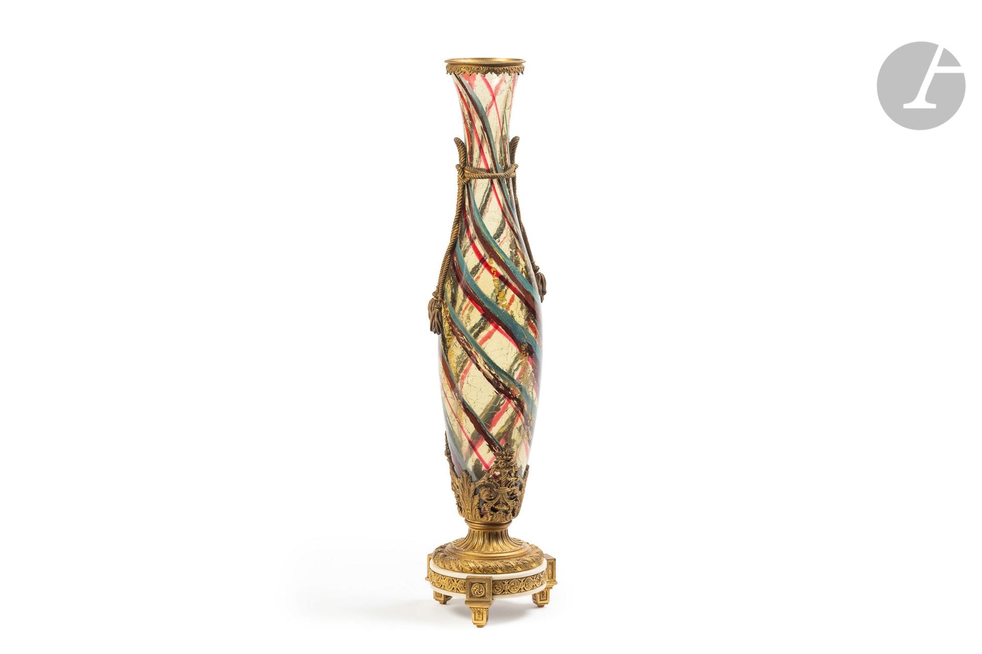 ERNEST-BAPTISTE LÉVEILLÉ (1841-1913) & PAUL LOUCHET (1854-1936)
Abstraction
Très important vase fuselé présenté dans une monture en bronze doré réalisée par Louchet fondeur-ciseleur.
Épreuve en verre miel crispé au décor polychrome intercalaire enrichi de feuilles d’or éclatées également en intercalaire.
La monture présente une couronne de laurier surmontée de cannelures en partie basse, un cerclage aux motifs de lambrequins en pourtour du col et des cordons façon passementerie en chute de l’épaulement.
Hauteur : 65,8 cm