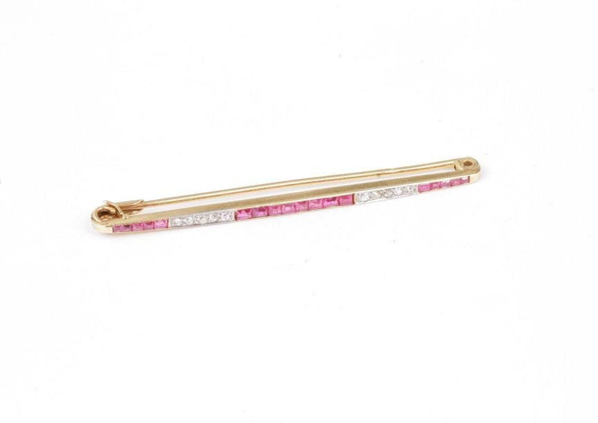 18K (750) gold bar brooch, set with calibrated ru alternated with old cut round diamonds. French work from the 1920s. Length: about 6 cm. Gross weight: 3.9 g (shock)