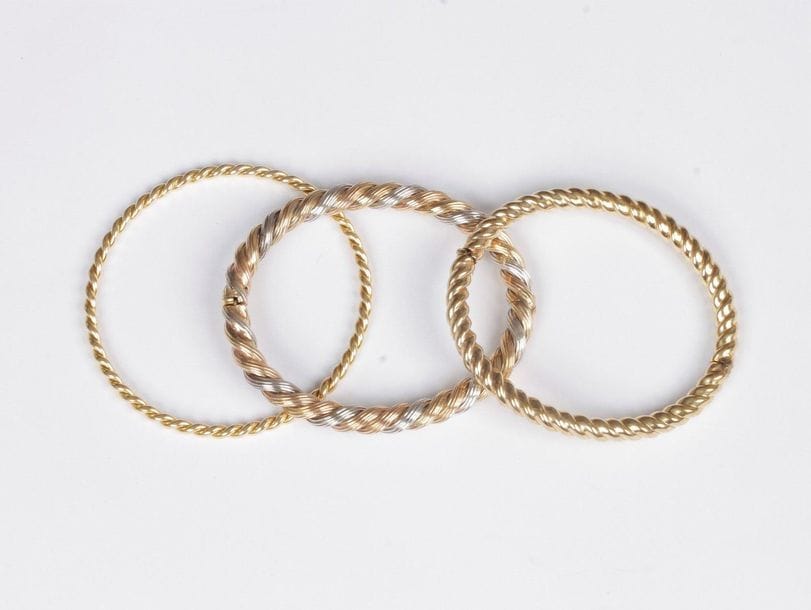Suite de bracelets torsadés, l’un en or 18K (750), les deux autres en or 9K (375). Poids : 64,8 g