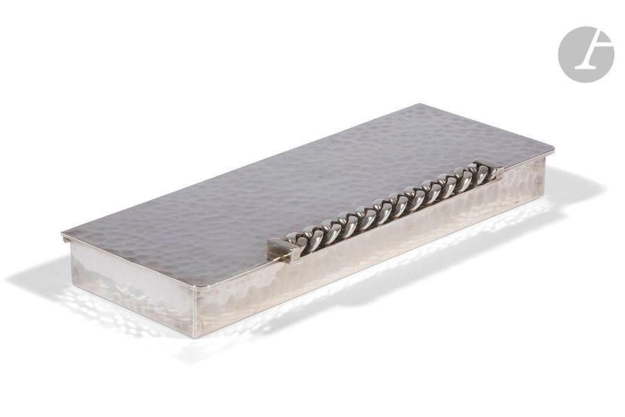 JEAN DESPRÉS (1889-1980
)Cigarette box. Silver metal print with hammered surface. The grip formed by a flat-link bracelet in application. Signed J. DESPRÉS, with the point on the reverse. H. 3 cm - W. 22.5 cm - L. 9 cm
