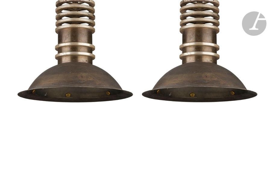 TRAVAIL MODERNISTE DES ANNÉES 1930
Paire de suspension en laiton patiné. Chaque coupe hémisphérique est surmontée d’un cylindre orné de bagues en métal argenté. Manquent probablement des cache-ampoules, oxydations, altérations aux parties argentées. H. 40 cm – D. 39 cm