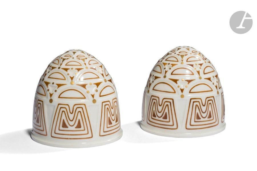 MANUFACTURE NATIONALE DE SÈVRES – HENRI RAPIN (1873-1939) & JEAN-BAPTISTE GAUVENET (1885-1967) CONCEPTEURS DE LA FORME
Motifs géométriques, 1925
Paire de tulipes cache-ampoules de forme obus à gradins. Épreuves en porcelaine (pâte dure translucide). Les décors polychromes et à l’or au four sur fond ivoire. Chaque pièce marquée des cachets noirs date S – 1925 6 DN et rouges R.F. Décoré à Sèvre 1925 et Made in France à l’intérieur. H. 11 cm

Bibliographie : 
Les œuvres de la Manufacture Nationale de Sèvres 1738 – 1932 – Volume V Le luminaire – Édition de la Manufacture Nationale de Sèvres, 1932. Des modèles identiques, aux décors différents, reproduits planches I et II sous les références 3504 et 3505.