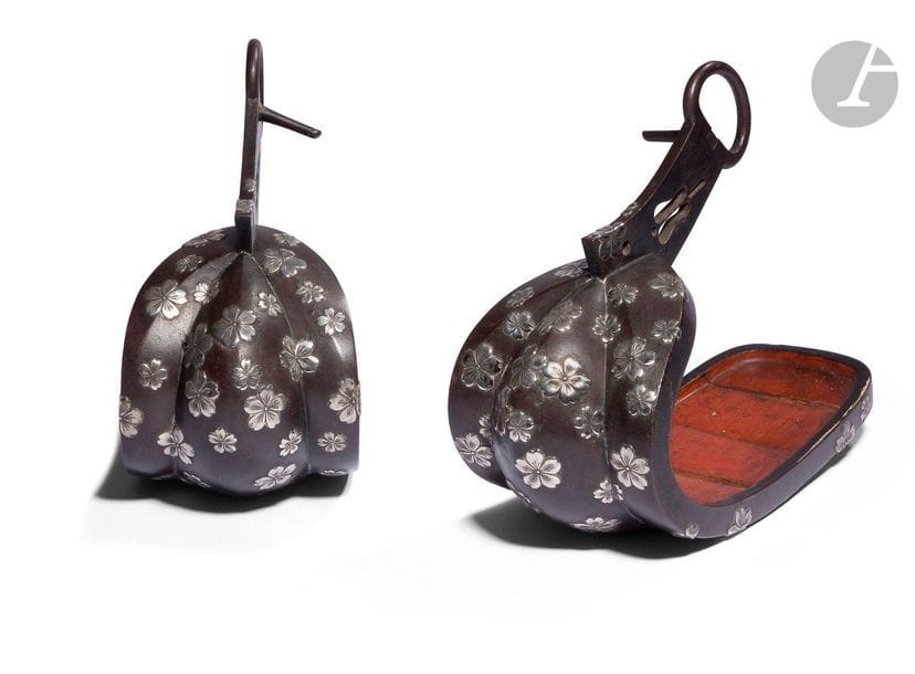 JAPON - XIXe siècle
Paire d’étriers (abumi) en bronze à patine brune à décor en shibuichi de fleurs de cerisiers en relief, l’intérieur en bois laqué rouge. 
H. 23,8 cm