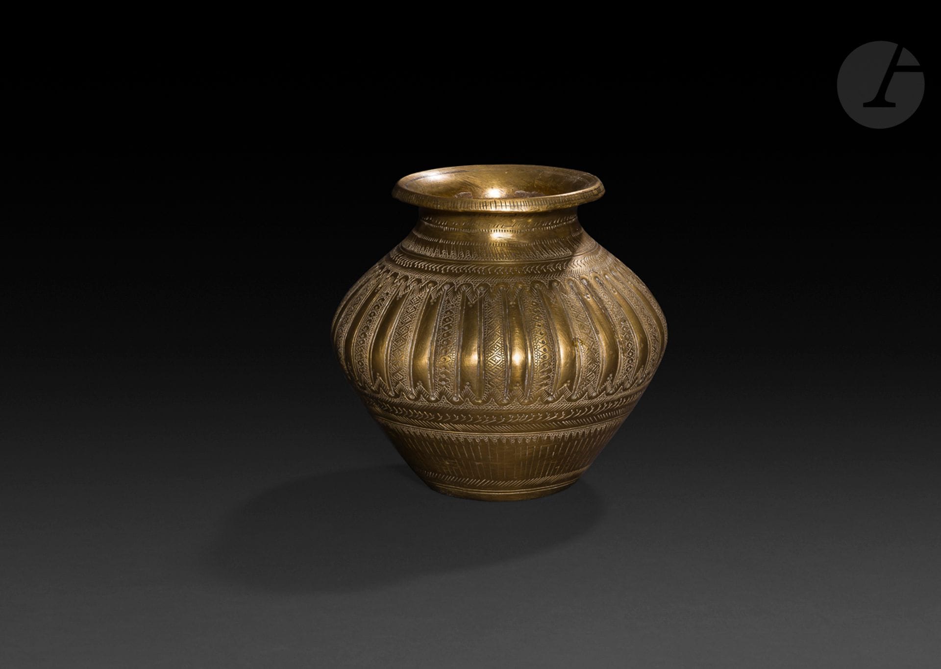 Deux vases lota, Inde, fin XIXe- début XXe siècle
L’un en laiton, panse carénée et godronnée, col étranglé achevé par une lèvre ourlée. Décor gravé de frises de chevrons, triangles, croisillons agrémentés de petits cercles. Hauteur : 15 cm ; l’autre en laiton, à panse globulaire à col cylindrique légèrement évasé. Décor émaillé polychrome et gravé de tiges végétales et d’une frise d’éléphants sur l’épaule. Base plate tripode gravée d’une corolle de fleur. Hauteur : 14 cm ; petit trou, fines rayures.

Two lota vase, India, late 19th-early 20th century