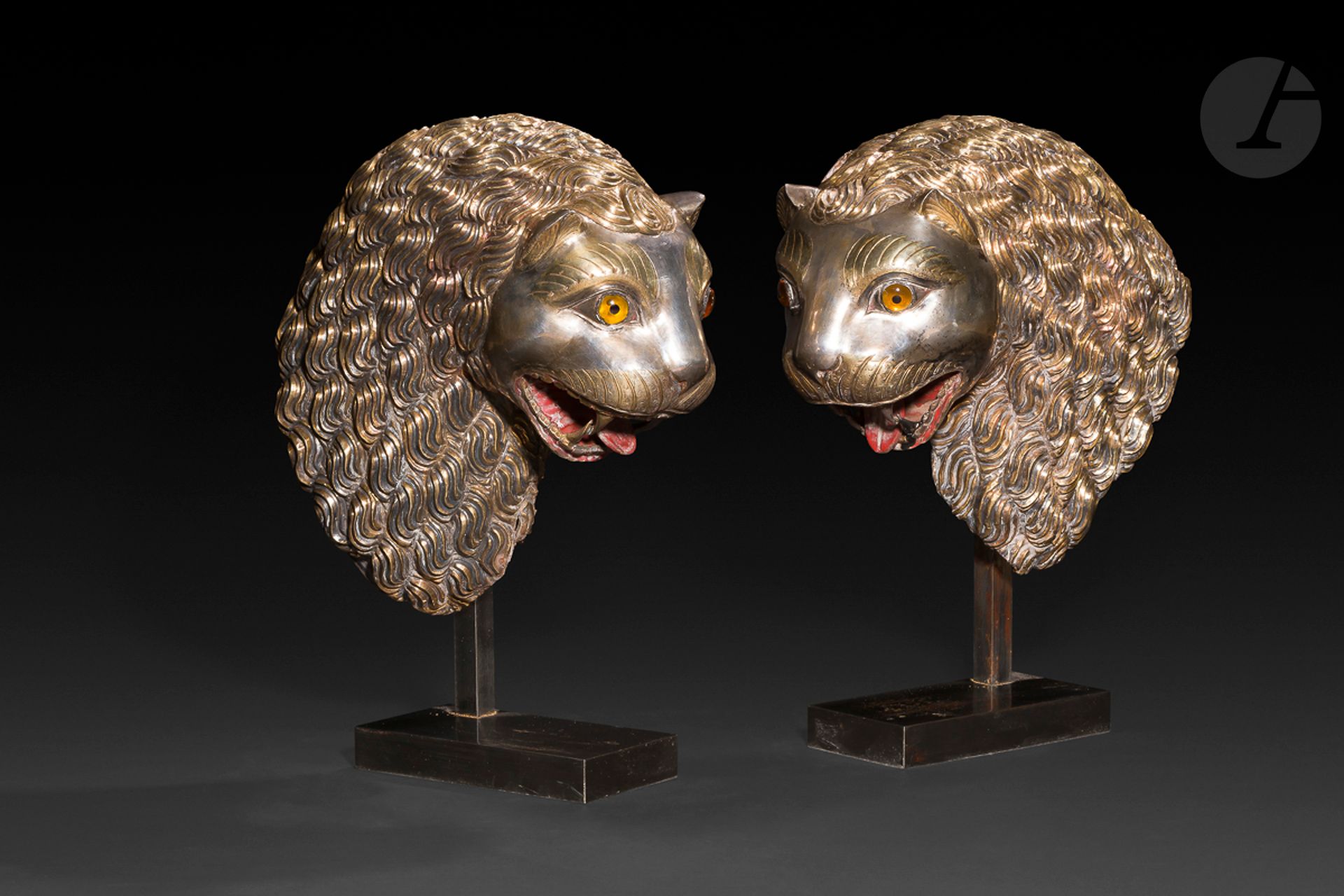 
Paire de têtes de lion en ronde-bosse, Inde du Nord, probablement Rajasthan, XIXe siècle

Deux protomés de lion à la crinière ondulée et la gueule ouverte constitués de plaques d’argent sur une âme de bois sculpté, les crinières en argent teinté. Incrustations de résine pour les yeux, détails ciselés sur l’argent et peinture rouge dans la gueule.

Hauteur : 35 cm

Accidents, montés sur socles.



Two silver finials in the form of lion heads, North India, probably Rajasthan, 19th century



 Ce type de ronde-bosse venait orner les montants ou accoudoirs des trônes ou palanquins howdahs des maharajahs comme ceux exposés au fort Mehrangarh de Jodhpur.
