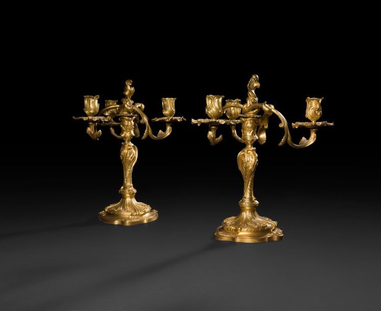 Pair of three-light gilt bronze candelabra, the shaft with an animated shape decorated with rockeries and piastres, the removable bouquet (associated) decorated with rockeries and foliage.
Louis XV period.
Torch, H: 25 cm; 
H (total): 34 cm