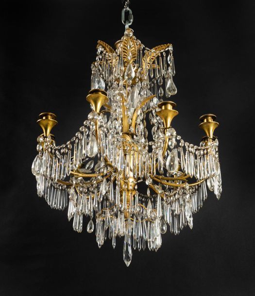 *Lustre en bronze doré et verre taillé à dix lumières, le fût entièrement de bronze doré à décor de têtes féminines, rinceaux et godrons dans un entourage de pendeloques en couronnes circulaires, surmonté de palmettes.
Époque Consulat.
H : 85 cm, D : 56 cm 

Provenance :
Ancienne galerie Marcel Bisset.