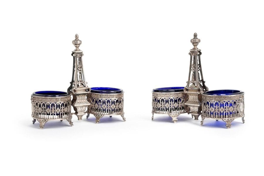 FRANCE XIXe SIÈCLE
Paire de doubles salières en argent estampé de style Louis XVI, complète de leurs verrines en verre bleu, la prise figurant un obélisque ajouré. Chiffrée de lettres entrelacées dans des médaillons.
Poids net : 283,70 g