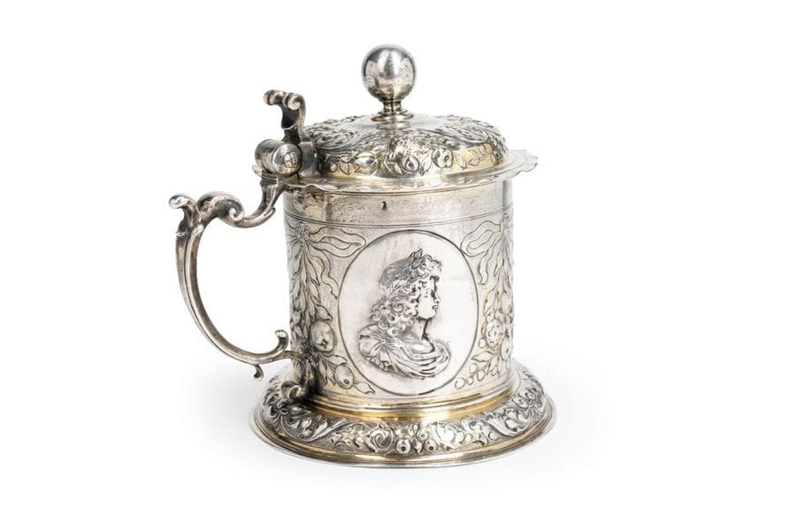 AUGSBURG 1692 - 1700Chope
with lid (humpen) in vermeil. It rests on a circular pedestal embossed with scrolling motifs alternating foliage and fruit in a recessed pattern on the lid. The body has three profiles in medallion representing Leopold I of Habsburg (1640 - 1705), his wife Empress Eleanor (1655 - 1720) and their son Joseph I (1678 - 1711) crowned king of Hungary in 1687, between motifs of ribbon knots and fruit. Handle with inverted windings.
Onomastic hallmark of an unidentified master goldsmithWeight
: 417.5 g - height: 16 cm 
Condition: weak to vermeil



