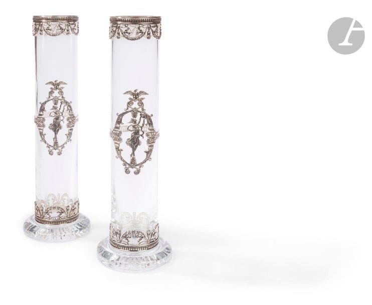 PORTUGAL - PORTO XXe siècle
Paire de vases circulaires en cristal monture en argent estampé ajouré 925 ‰. Ceinturée en partie basse et haute d’un décor de guirlandes de lauriers et de nœuds de ruban, la partie centrale est rehaussée sur une face d’une bacchante frappant son tambourin dans un encadrement de coupes d’abondance surmontées de fruits et d’un aigle tenant la foudre dans ses griffes (Jupiter).
Poids brut : 4472,80 g - hauteur : 38,8 cm - diamètre : 7,8 cm