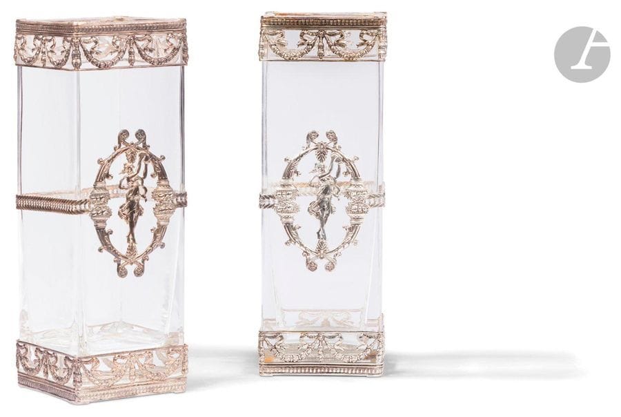 PORTUGAL - PORTO XXe siècle
Paire de vases carrés en cristal monture en argent estampé ajouré 925 ‰. Ceinturée en partie basse et haute d’un décor de guirlandes de lauriers et chute de nœuds de ruban, la partie centrale est rehaussée sur une face d’une bacchante frappant son tambourin dans un encadrement de coupes d’abondance surmontées de fruits.
Orfèvre : TOPAZIO
Poids brut : 5348 g - hauteur : 29,5 cm