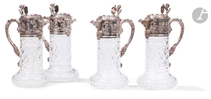 PORTUGAL - PORTO XXe siècle
Ensemble de quatre aiguières en cristal taillé et monture en argent 925 ‰. De forme circulaire, le cristal reçoit dans sa partie supérieure une frise repoussée sur deux faces de scènes figurant des putti dansant et jouant encadrant un bec verseur souligné d’une tête de Bacchus, et une anse à l’imitation d’un cep de vigne. L’appui-pouce du couvercle à charnière figure un lion héraldique tenant un blason dont le champ est laissé vierge de gravure.
Orfèvre : TOPAZIO
Poids brut : 6883,6 g - hauteur : 28,5 cm - diamètre de la base : 13,5 cm