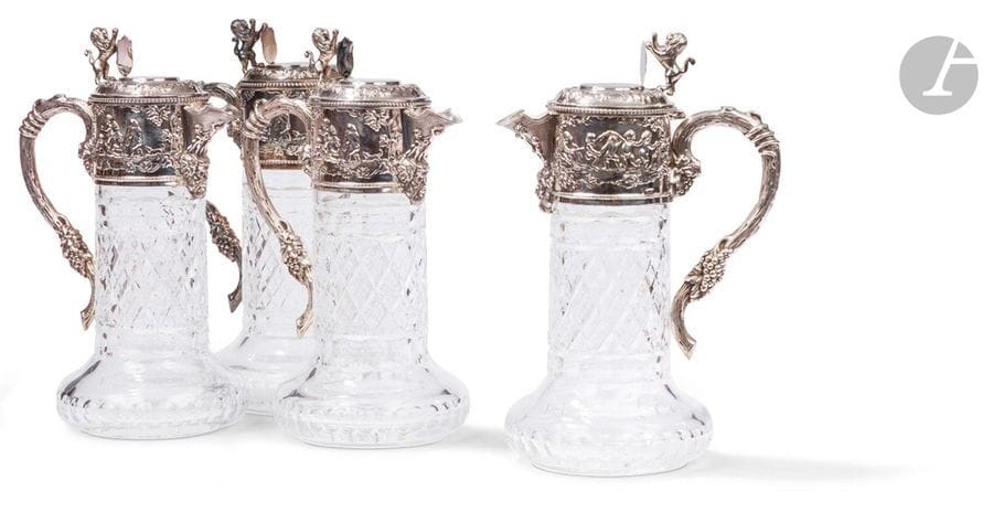 PORTUGAL - PORTO XXe siècle
Ensemble de quatre aiguières en cristal taillé et monture en argent 925 ‰. De forme circulaire, le cristal reçoit dans sa partie supérieure une frise repoussée sur deux faces de scènes figurant des putti dansant et jouant encadrant un bec verseur souligné d’une tête de Bacchus, et une anse à l’imitation d’un cep de vigne. L’appui-pouce du couvercle à charnière figure un lion héraldique tenant un blason dont le champ est laissé vierge de gravure.
Orfèvre : TOPAZIO
Poids brut : 6883,6 g - hauteur : 28,5 cm - diamètre de la base : 13,5 cm
