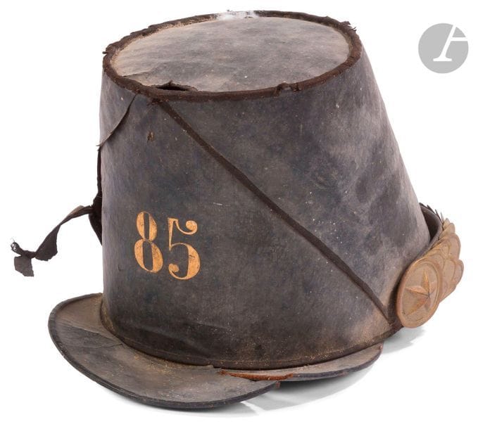 Shako d’officier du 85e de ligne. 
Fût en carton avec couvre shako en toile enduite peint du chiffre 85 à l’or. Jugulaires en écailles et rosaces à l’étoile en laiton doré. 
Étiquette intérieure de Prevel. 
Dans l’état. Second Empire.