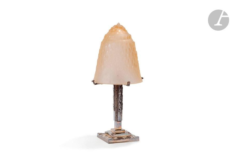 MULLER FRÈRES LUNÉVILLE & TRAVAIL FRANÇAIS
Lampe de salon. Le pied en bronze (re)argenté aux motifs géométriques. Le cache-ampoule, rapporté et non d’origine, en verre rose pâle moulé-pressé aux motifs en relief évoquant de la glace. La verrerie signée MULLER Fres Lunéville. H.46cm 