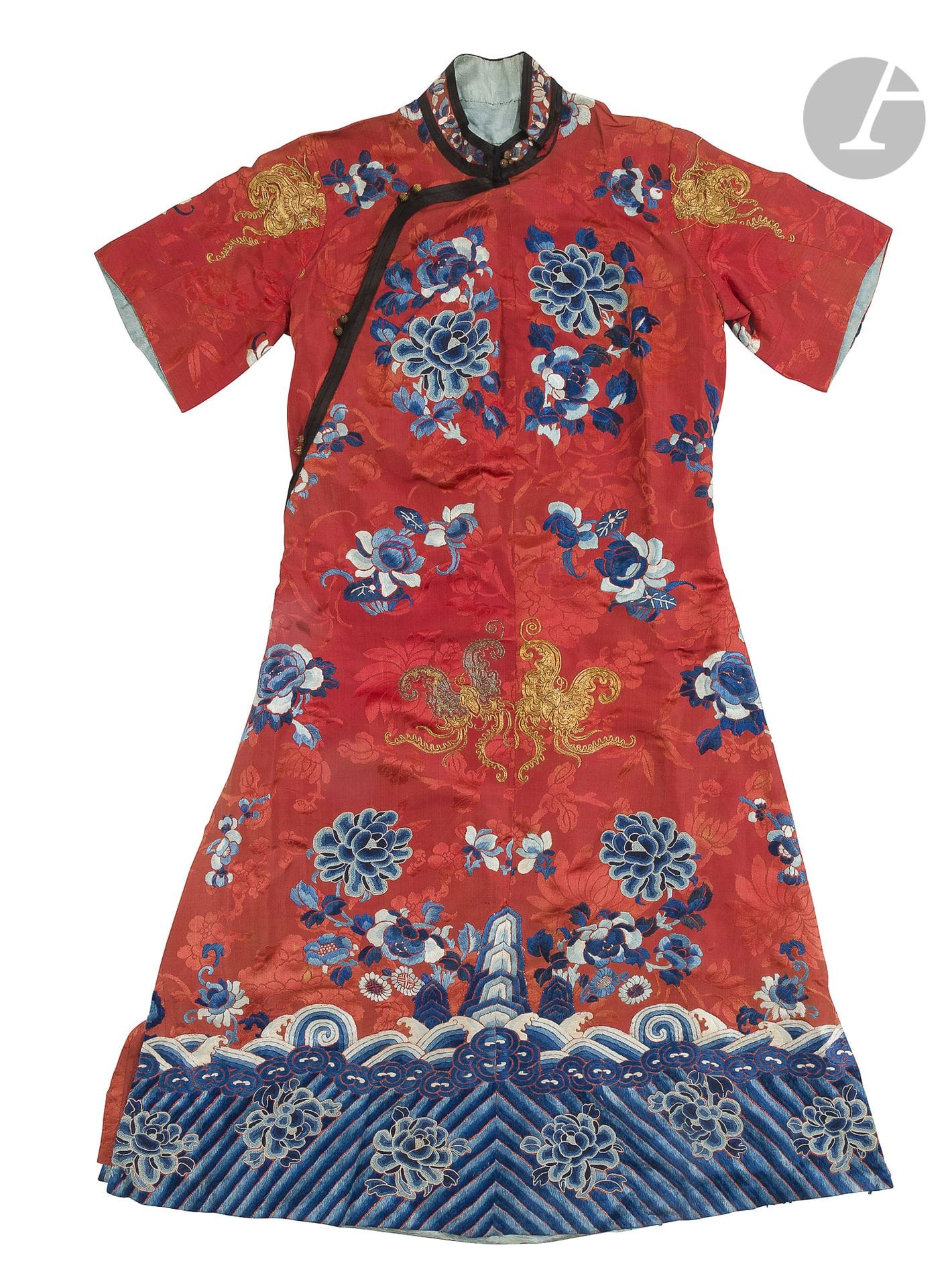 A woman's cheongsam or Qipao dress, in red silk satin printed with flowers and embroidered, China, early 20th century. The
red background is printed with peonies and cherry blossoms and embroidered with blue and white silks of cherry blossoms, peonies, lotus blossoms, melons and butterflies in gold thread. The lower band is decorated with peonies on oblique li shui lines topped with waves, from which the three rocky peaks of the Earth emerge. The sleeves are short and the plain blue lining is printed with flowers. A pair of cream silk pants is attached.
Dress length: 111.5 cm; shoulder width: 76 cm; pants length: 103 cm; waist width: 33 cmAccidents
.


