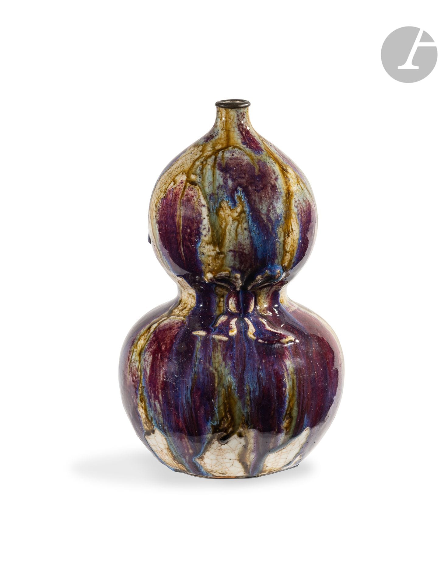 Flamed porcelain double-gourd vase, China, late 19th - early 20th centuryA
blue, purple and brown flamed glaze on a cracked cream ground. The narrowing at the level of the body decorated with a knot in relief carved in the paste and enamelled. The neck is probably lapped, mounted with a metal ring. The enamel flows are lapped at the foot. Inventory labels under the heel.
Height : 30 cm

