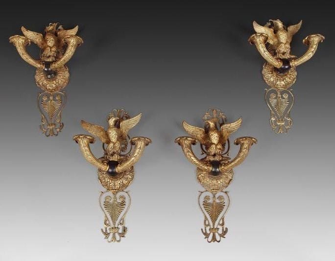 Suite de quatre appliques à deux bras de lumières en bronze ciselé, doré et patine brune à décor d'un aigle les ailes déployées et palmettes ajourées. Époque Restauration. Hauteur: 33 cm - Largeur: 17,5 cm Montées à l'électricité.