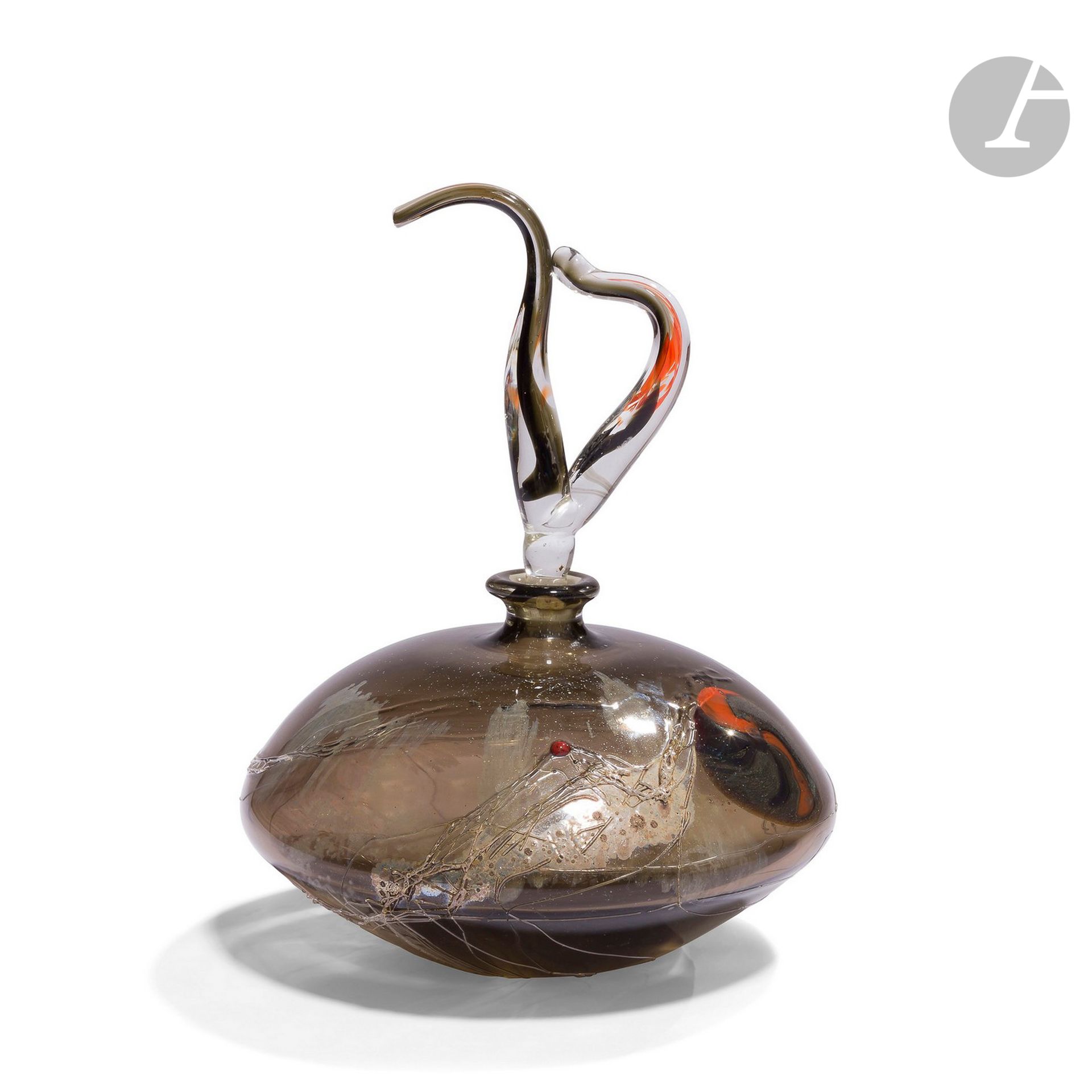 DOMINIQUE MARCADE [français]  (né en 1960)
Flacon en verre soufflé épais teinté, à décor intercalaire orange et gris. Fils de verre et oxydes métalliques appliqués en surface, bouchon polychrome de forme libre. Signé et daté 1991 sous la base. 
H. 23 cm - D. 16 cm

Bibliographie :
Catalogue de l’exposition Papier de verre, Salon d’Art contemporain de Rouen, Galerie Complément d’Objet, 1991. Pièce reproduite page 15.
