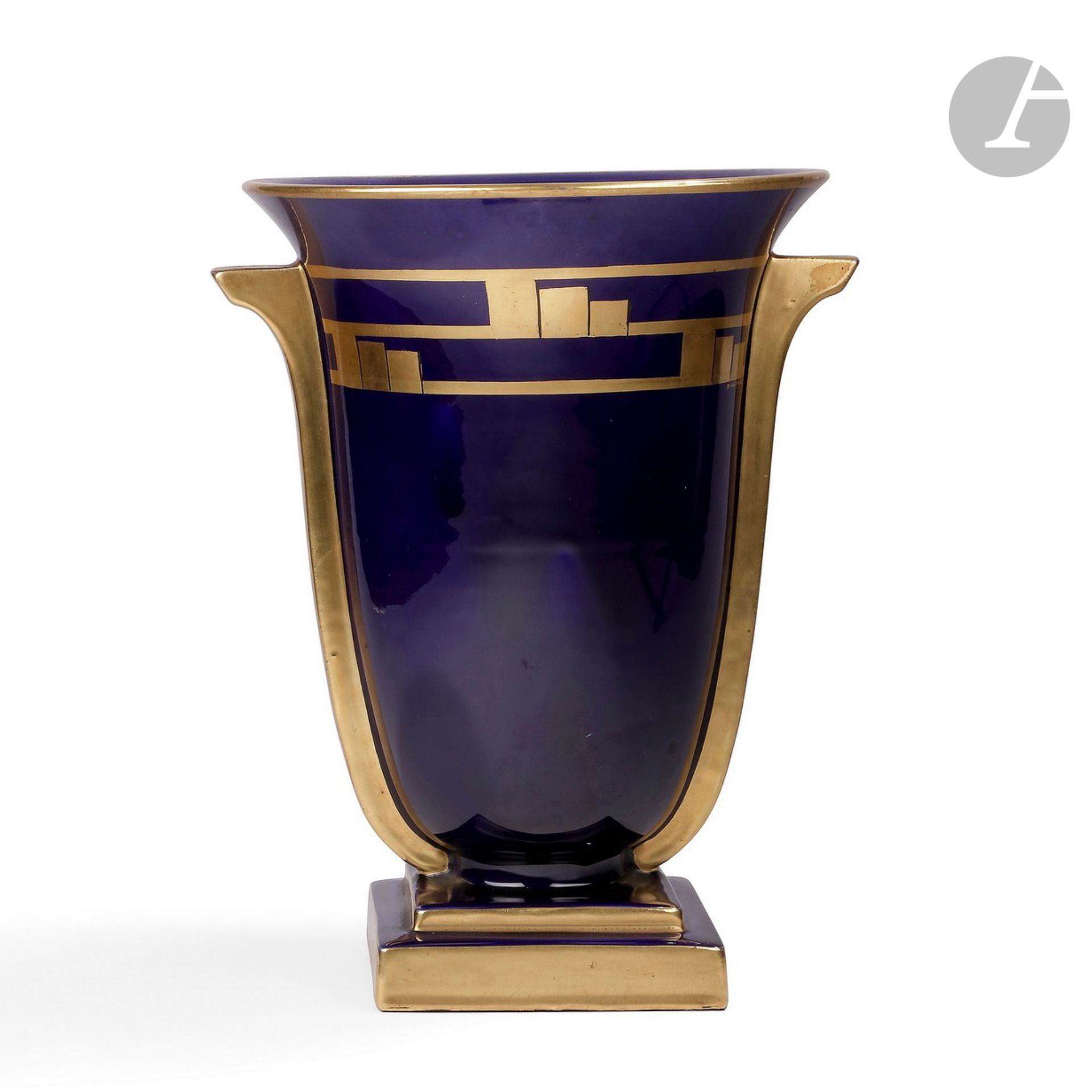 MANUFACTURE JAGET-PINON À TOURS 
Frise de motifs géométriques
Vase cornet à ailettes reposant sur une base carrée à un gradin. Épreuve en céramique émaillée bleu de four ; le décor titre, les ailettes et les tranches de la base à l’or au four. Années 1930. Signé PINON-MAURICE sous la frise décorative et porte le cachet de la manufacture sous la base. H. 32,5 cm