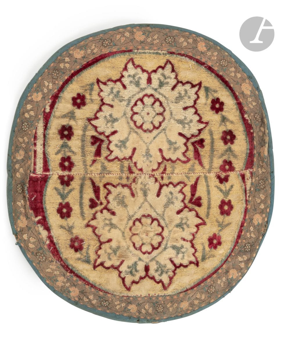 Velours à décor floral, Turquie ottomane, XVIIe siècle
Deux fragments semi-circulaires de velours grenat brodé de fils de soie d’un décor de rosace florale au cœur en rosette cerclé d’une guirlande de jacinthes et encadrée de deux branches de prunus rouge. Deux fragments cousus ensemble pour former une pièce ronde et doublés d’une pièce de coton tissée en bordure d’une frise florale.
42,7 x 38,5 cm
Forte usure, assemblage plus tardif.

Provenance : 
Ancienne collection Hagop Kevorkian (1872-1962). 

A panel formed from two pieces of an Ottoman velvet, Ottoman Turkey, 17th century

