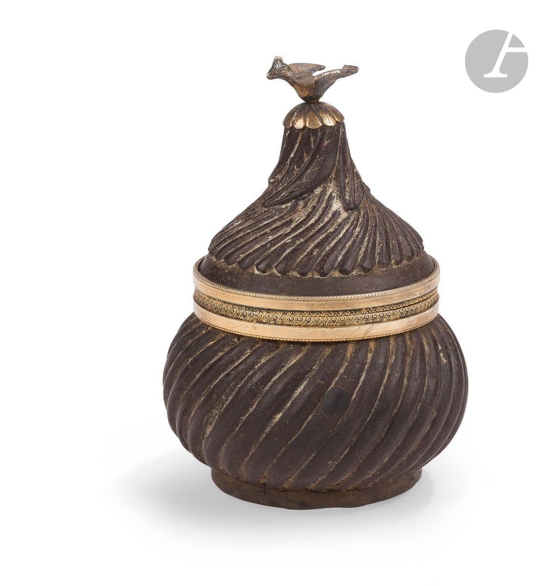 Ambergris and vermeil sweetmeat, Ottoman Empire, 19th
centuryAmbergris globular
box with
domed lid decorated with swirling stripes. The lid finished with a vermeil aviform grip emerging from a plant corolla and the base encircled with a vermeil mount taken up on the top of the body.
Height: 11 cm

Numerous legends have developed around ambergris, making this material ever more mysterious: if the Chinese, 2000 years BC

, called it "perfume", it is because it is a natural product.

C. called it "dragon's slime perfume", Avicenna thought that ambergris came from an underwater fountain, probably inspired by the Thousand and One Nights where Sindbad the sailor sees amber gushing out of a spring before it is swallowed by sea monsters... In reality, it is a secretion that forms in the stomach or intestines of the sperm whale and is then rejected by the animal's natural ways. Fossilized by time, sea salt and the sun, it is recovered from the surface of the water or washed up on the beaches where it is collected in blocks. Since the highest antiquity, men find medicinal virtues to it but also odoriferous and aphrodisiac. From a medical point of view, it has long been used as a remedy for asthma and epilepsy. The Arabs also used it to treat joints, digestive disorders, the heart and the brain. Arrived in Europe in the Middle Ages at a high price, it was worn as a necklace, often set in a piece of gold-plated jewellery called a scented apple or pomander, and breathed in to strengthen one's immune system against health scourges such as the plague. A powerful scent-fixing agent, ambergris was an essential component of 20th-century perfumes; today it has been replaced by synthetic accords. The aphrodisiac effect of the resin was recognized very early, already in ancient China. In 18th century Europe, libertines, like the great Casanova, used to perfume their hot chocolate with it to be invigorated. The resin was also used to perfume women's gloves and could be consumed in the form of lozenges to be sucked. The seductive power of ambergris did not escape the Ottoman sultans who used it daily in the form of tablets to be dissolved in hot coffee. Our object, whose body and lid were entirely made of this rare material, shows a different use in the Ottoman context than the "pastilles du sérail" so called by the French: we find the idea of the sweet apple appreciated in medieval Europe diffusing powerful odours in the room where it was placed or perfuming the objects which could be contained inside.

An Ottoman ambergris and silver-gilt pomander, 19th century







