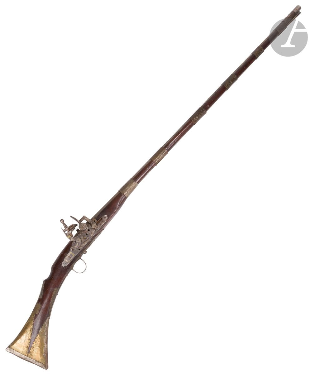 Flintlock rifle, mukhala, North Africa, 20th centuryLong
wooden barrel with metal rings chased with geometric decoration, three of them with dirham charms. Stock and breech with brass, copper and silver plate fittings. Flintlock lock.
Length: 144,5 cm Traces of
rust. 

A flintlock gun (mukhala), North Africa, 20th century






