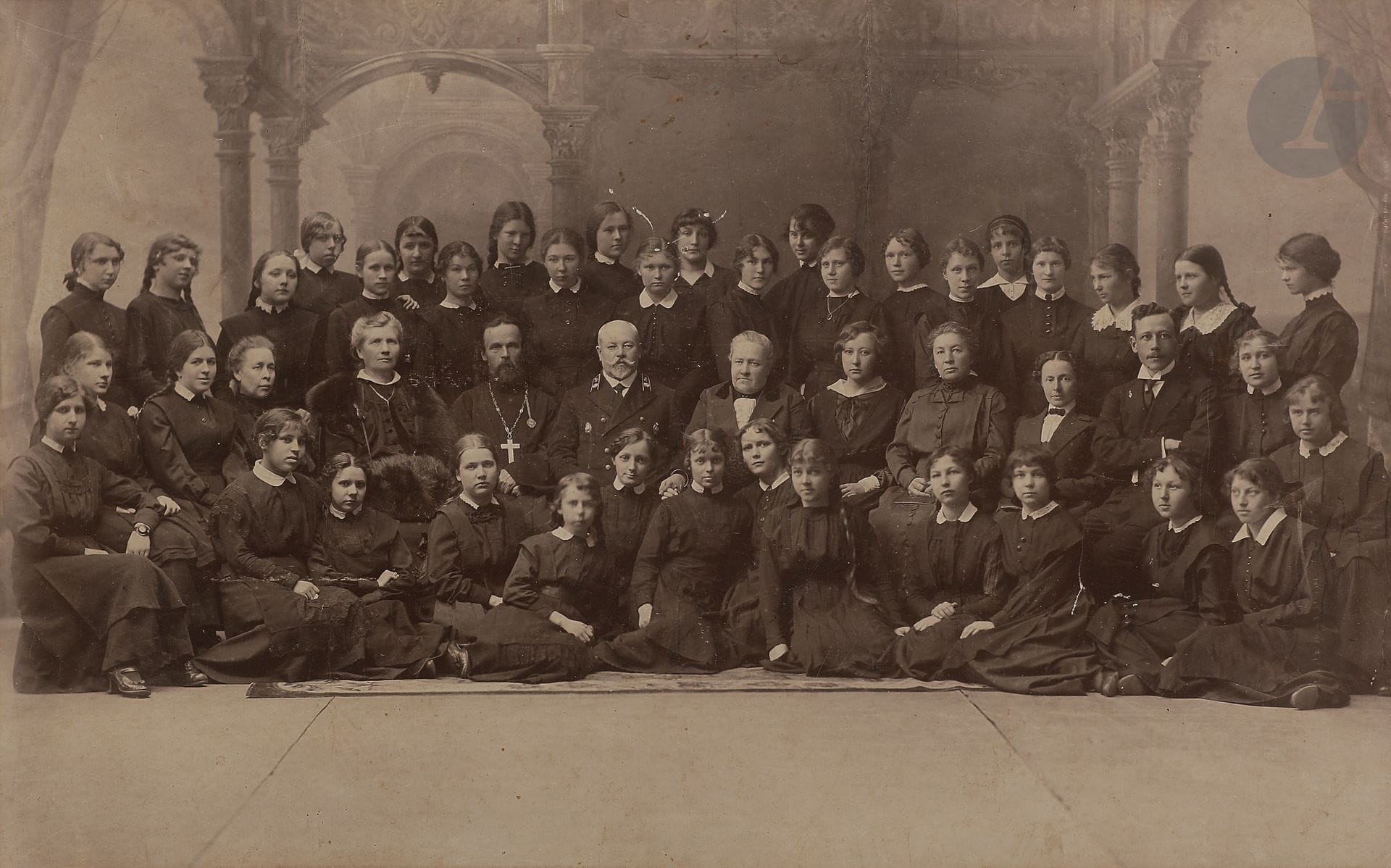 Photographie de la promotion de la VIIe classe du collège Marie d’Arkhangelsk, 1916
Toutes les jeunes filles de la classe (sauf une) présentes sur la photographie sont nommées (parfois avec leur prénom). Sur la rangée du milieu, les enseignants présents sont de gauche à droite, après deux élèves : Maria Arkadievna Koursina, Agnia Ivanovna Vitol (Allemand), père Ioann Diakonov (catéchisme), Vladimir Feofilaktovitch Kortchaguine (conseiller d’État, président du conseil pédagogique), Ekaterina Pavlovna Protopopova (directrice du collège), Elisaveta Nikolaevna Samsonova, Nina Illarionovna Mirotvortseva (histoire), Olga Vladimirovna Kremmer (dessin), Alexandre Nikolaevitch Samsonov.
24 x 38 cm

Групповая фотография выпуска VII класса АРХАНГЕЛЬСКОЙ МАРИИНСКОЙ ГИМНАЗИИ. 1916
Графитным карандашом на обороте передаются фамилии (иногда с именем) всех воспитанниц  (кроме одной), даже тех, кого нет на фотографии. В среднем ряду преподаватели слева направо, после двух учениц : Марья Аркадьевна Курсина, Агния Ивановна Витель (немецкий язык), о. Иоанн Иванович Дьяконов (закон Божий), Владимир Феофилактович Корчагин (статский советник, председатель педагогического совета), Екатерина Павловна Протопопова (начальница гимназии), Елизавета Николаевна Самсонова, Нина Илларионовна Миротворцева (история), Ольга Владимировна Креммер (рисование), Александр Николаевич Самсонов.
24 х 38 см
Мариинская гимназия сыграла важную роль в развитии образования на Севере. Выпускницы гимназии, получив начальное педагогическое образование, составляли подавляющее большинство педагогических кадров на Русском Севере: они преподавали в начальных классах, работали домашними учительницами.