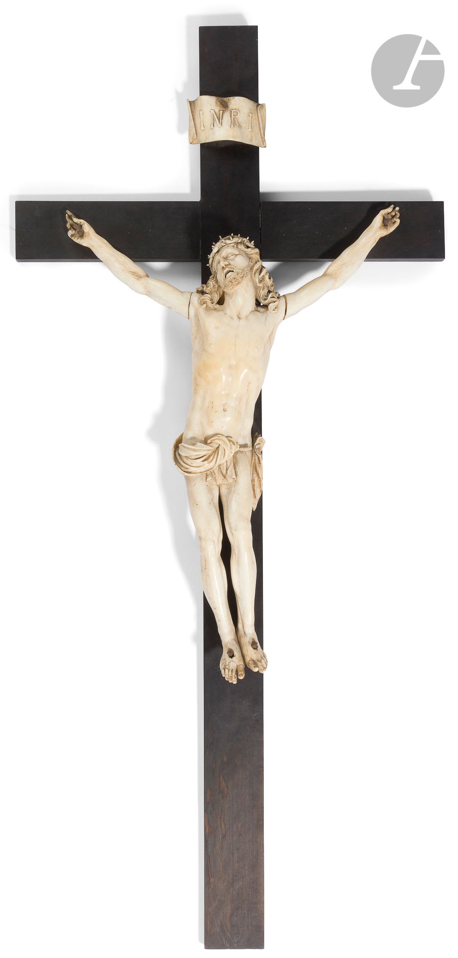 Crucifix avec Christ vivant en ivoire sculpté et croix en bois noirci. Tête levée vers le ciel, ceinte d’une couronne d’épines tressées, chevelure aux mèches bouclées reposant sur les épaules, bouche entrouverte, périzonium retenu par une cordelette, jambes parallèles.
XVIIe siècle.
Christ : H : 43 cm, L : 42 cm
H. totale : 86,5 cm
(Petites restaurations, accidents au périzonium).