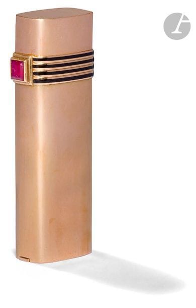 CHRISTIAN DIOR. Briquet à gaz en or jaune 750 0/00. Décor de 4 bandes émaillées noires et d’un rubis quadrangulaire. H : 7.1 cm. Pb : 99.81 g. Etui cuir façon crocodile.