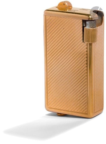 QUERCIA FLAMINARY for CARTIER. Gas lighter in gold 750 0/00. Decoration of diagonal flutes. Attachment buckle. Numbered: 017345. H: 6.2 cm. Pb : 88.07 cm. Monogrammed AM.