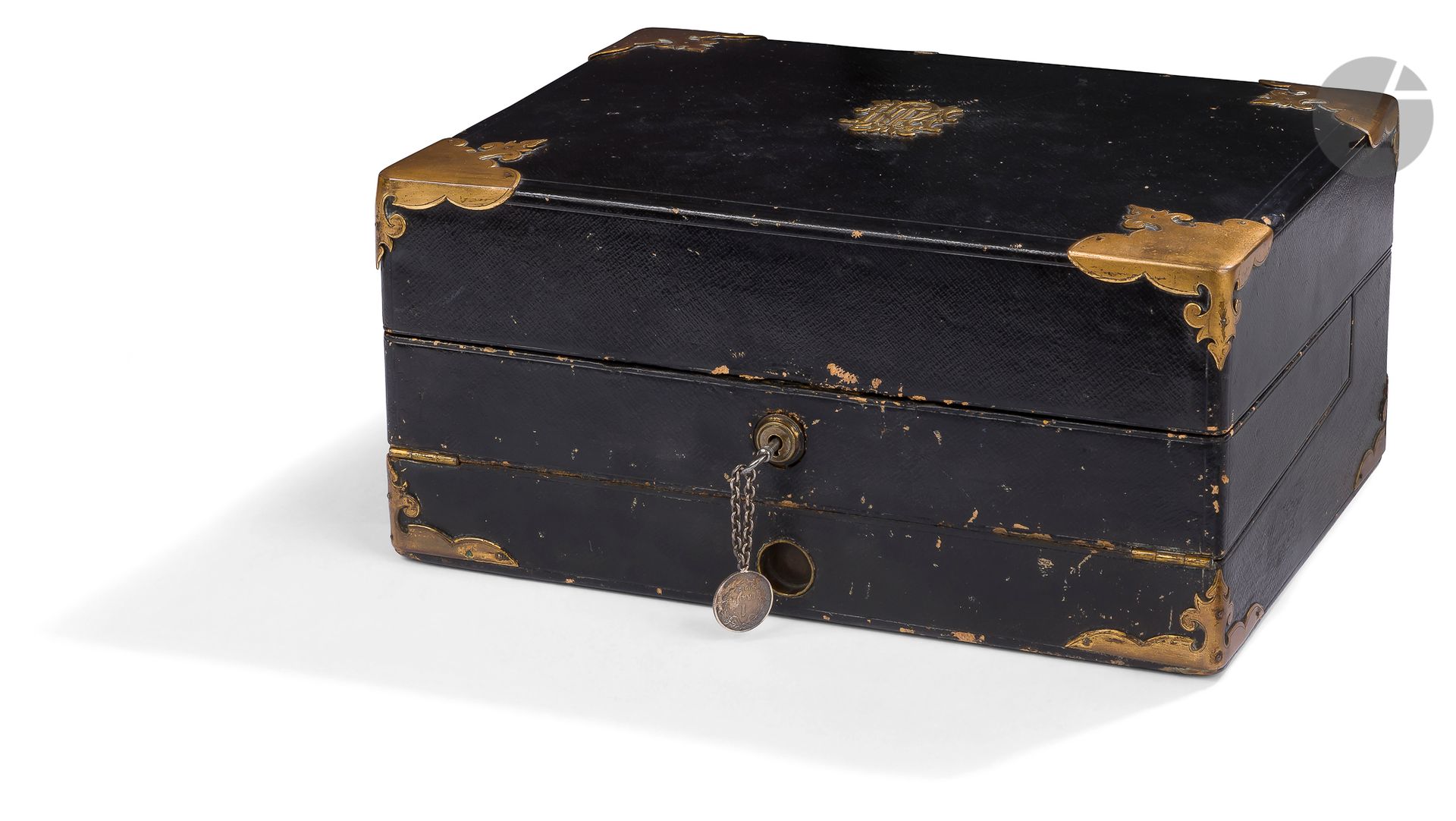 LEUCHARS & SON 38 & 39 Picadilly, London & 2 rue de la Paix, Paris.
Coffret formant écritoire de voyage en maroquin noir et laiton, le couvercle aux écoinçons festonnés, monogrammé en son centre découvre des casiers à papier, une boîte à allumettes (l’encrier manque), trois tablettes d’écriture, un battant mobile découvre deux compartiments de rangement.
Serrure marquée.
Vers 1860.
H : 15 cm, L : 32 cm, P : 24,5 cm
Usures d’usage et petits manques