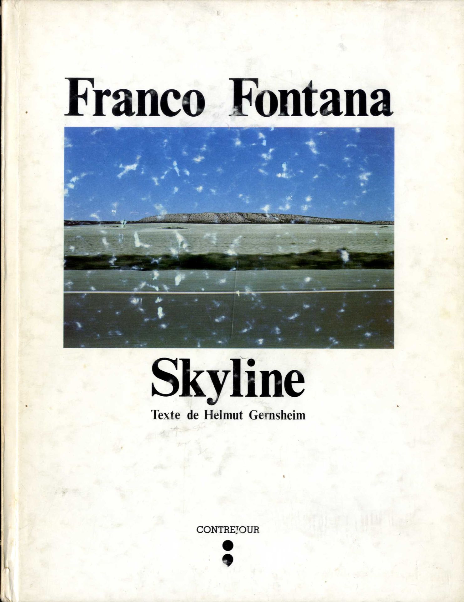 FONTANA, FRANCO (1933) [Signed]
Skyline.
Contrejour, Paris, 1978.
In-4 (21 x 27,5 cm). Édition originale publiée en France, signée par Franco Fontana en page de titre, 80 pp., 60 photographies en couleur pleine page, texte en français et en anglais d’Helmut Gernsheim. Couverture cartonnée rigide illustrée en couverture, défaut d’usage avec trace de frottement du premier et quatrième plat de couverture.

La mention du copyright comporte la mention « 2ème édition pour la France » mais cette mention est inexacte. En effet, l’édition publiée en Italie et l’édition publiée en France ont été réalisées simultanément ainsi qu’en atteste la liste des légendes photographiques en page 79, légendes qui figurent ici en italien sous le titre « Indice » et ainsi qu’en atteste l’achevé d’imprimé : « Finito di stampare nel mese di Febbraio presso le Grafiche STIG di Modena ». Seul le premier cahier avec l’introduction traduite en français a fait l’objet d’une impression différenciée au sein de la même imprimerie.