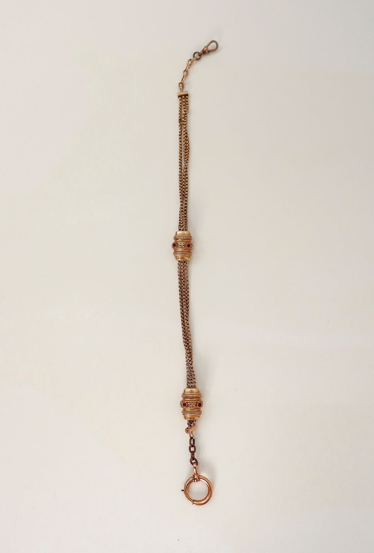 
Chaîne de montre en or (18K) et 2 coulants en or (14K) sertis de pierres rouges.

Poids brut : 33,4 g

(attaches en métal)
