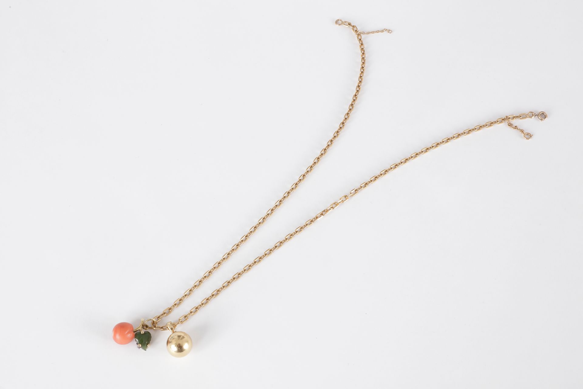 Collier en or 18K (750) retenant en pampilles, une boule en or et un pendentif dessinant une pêche en corail et feuille de néphrite.

Poids brut : 20,5 g