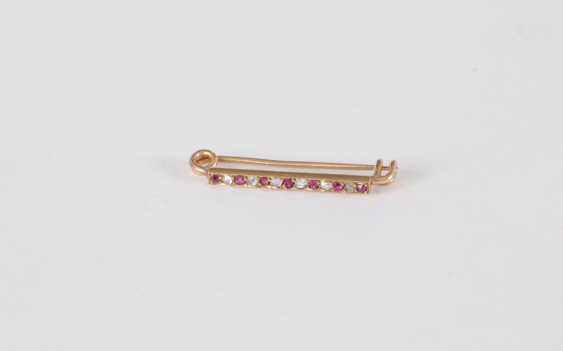 Broche-barrette en or 18K (750) sertie de rubis et de diamants taillés en roses.

Poids brut : 2,2 g
