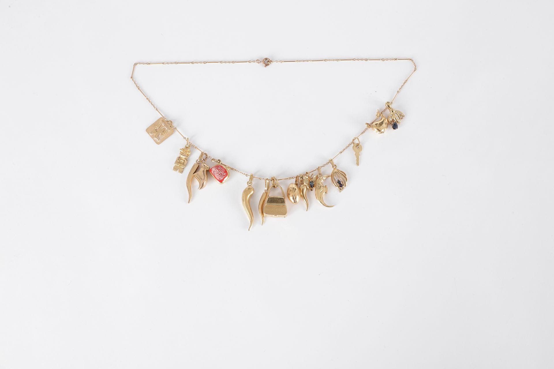 Collier en or 18K (750) retenant en pampilles 16 breloques en or dessinant des animaux, des accessoires et des portes-bonheur.

Poids brut : 17,7 g