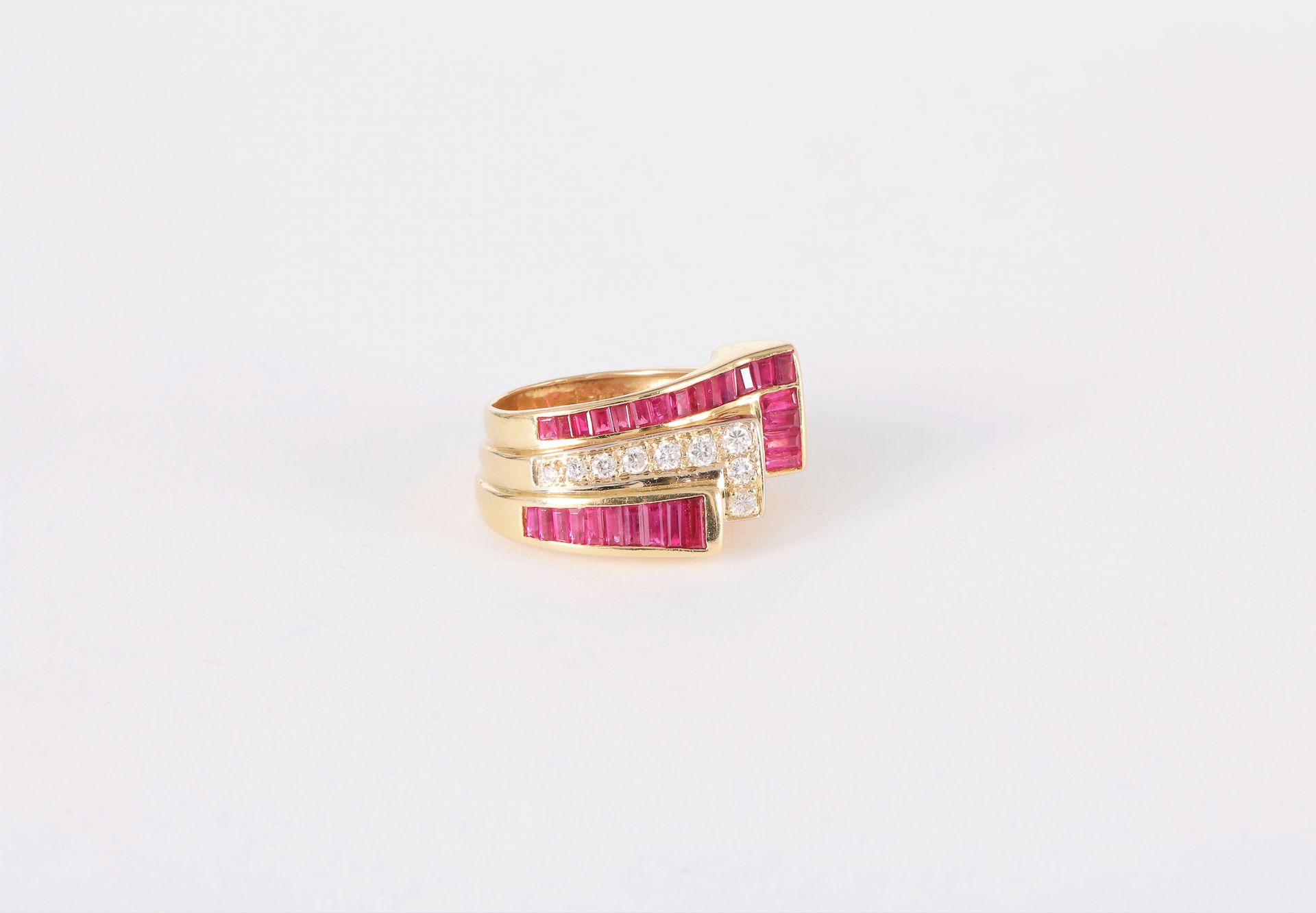 Bague asymétrique en or 18K (750) ornée d’une ligne de diamants ronds de taille brillant entre deux lignes de rubis synthétiques calibrés. Tour de doigt : 53/54

Poids brut : 9,7 g