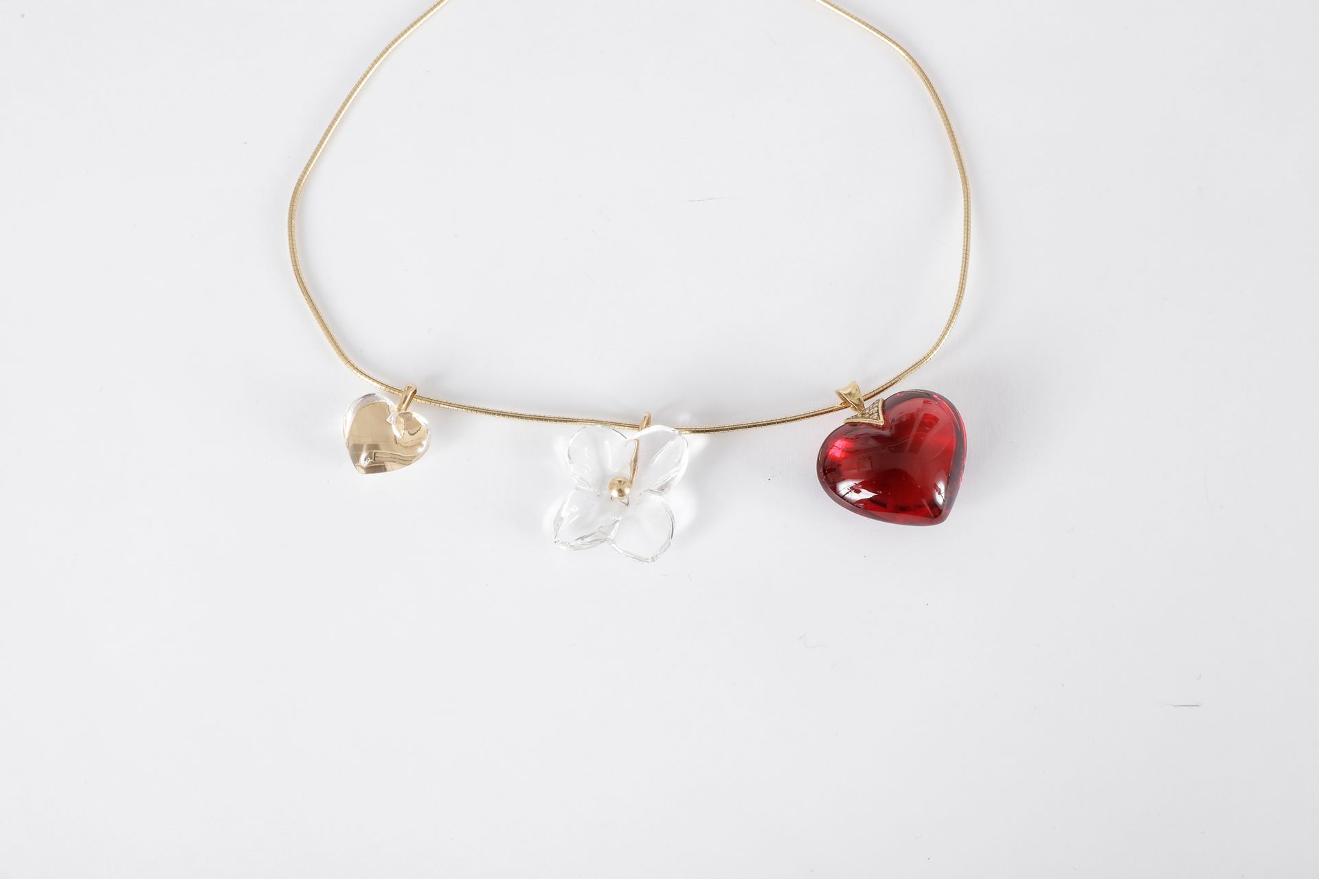BACCARAT. 

Lot de trois pendentifs en cristal montés en or : un cœur rouge, la bélière agrémentée de diamants, un coeur et un trèfle incolores, coulissant sur un collier cable en or 18K (750). Signés (sauf le collier)

Poids brut : 33 g (déformations)