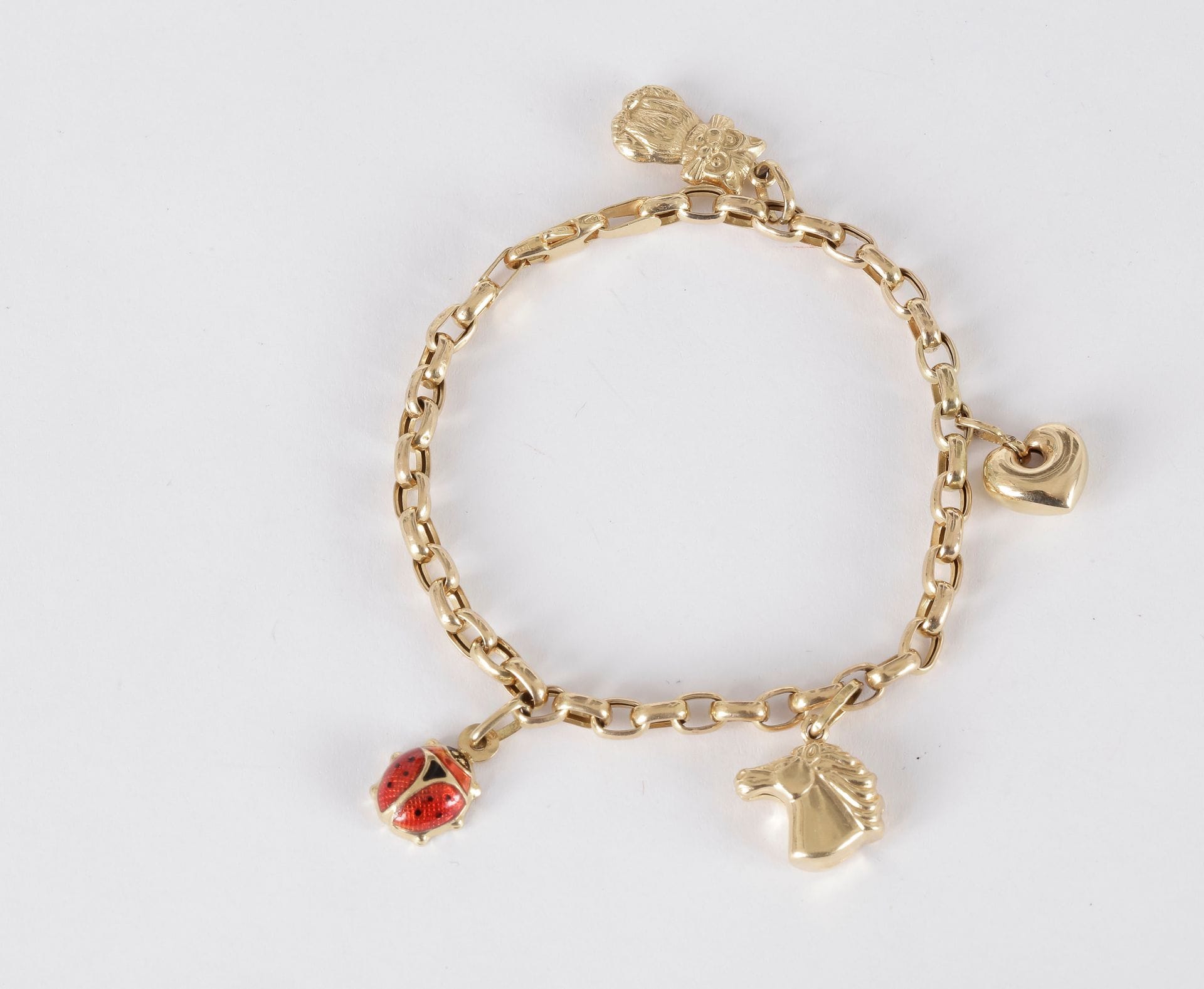 Bracelet en or 18K (750) retenant en pampilles 4 breloques : une coccinelle, une tête de cheval, un coeur et un chat. 

Poids brut : 8,8 g