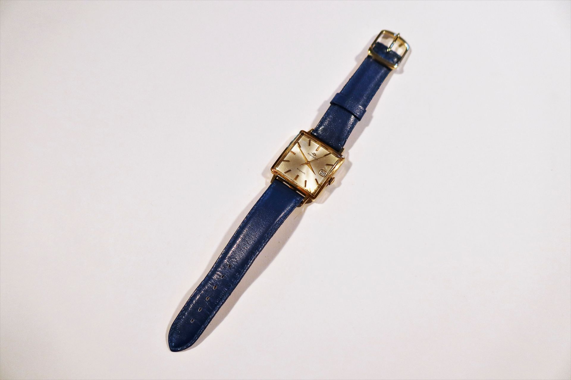 MOVADO Kingmatic 

Montre bracelet pour homme en or 18K (750), cadran blanc (accidents), index bâtons appliqués formant les heures, date par guichet à 3H, mouvement mécanique à remontage automatique, bracelet cuir.

Poids brut : 35,7 g